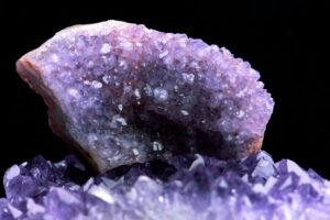 A photograph of a large amethyst crystal without background. The crystal is a deep purple color and has a faceted, shiny surface. The crystal is believed to have spiritual and healing properties, and is often used in meditation and other spiritual practices.